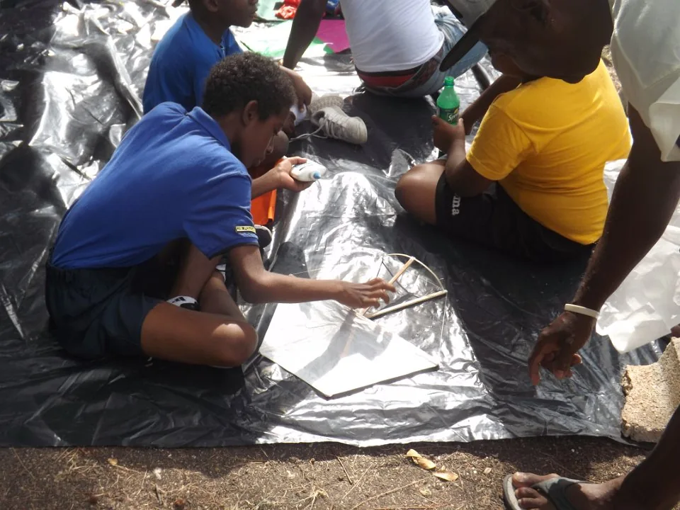 Adults and children working together on kite making.