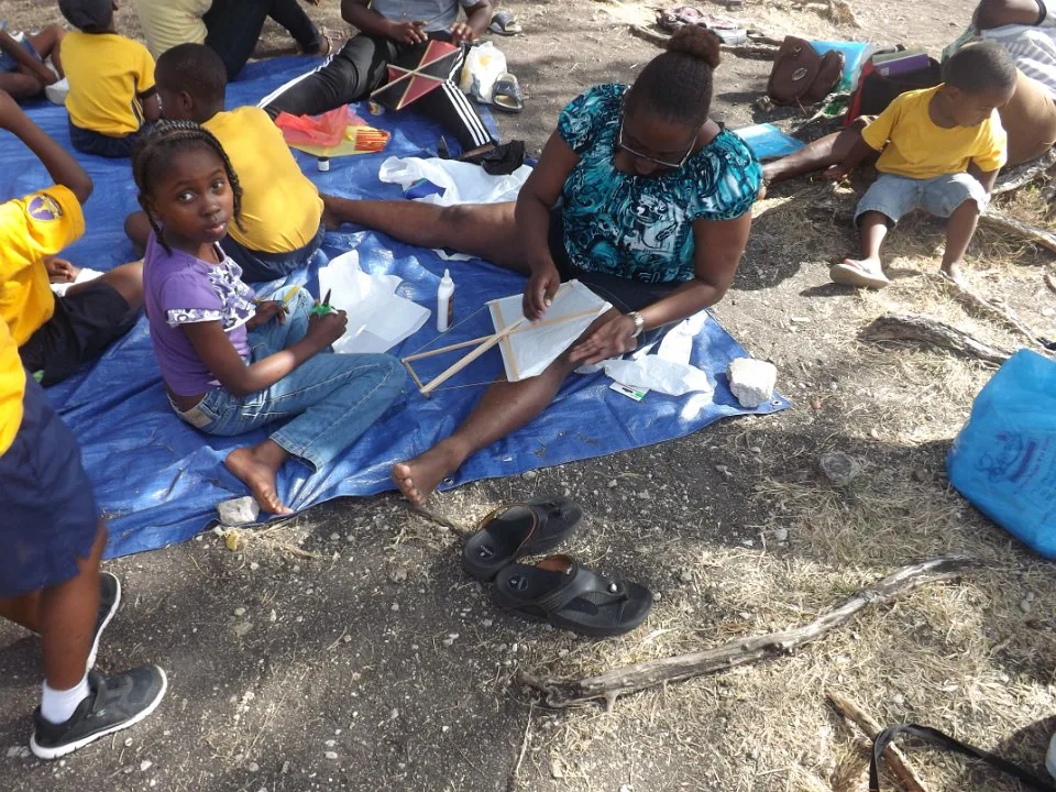 An adult helping children make kites.