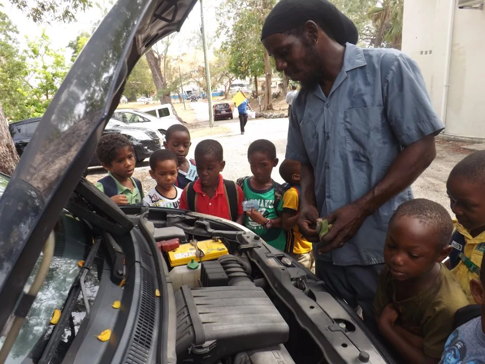 An adult explaining an engine to children.